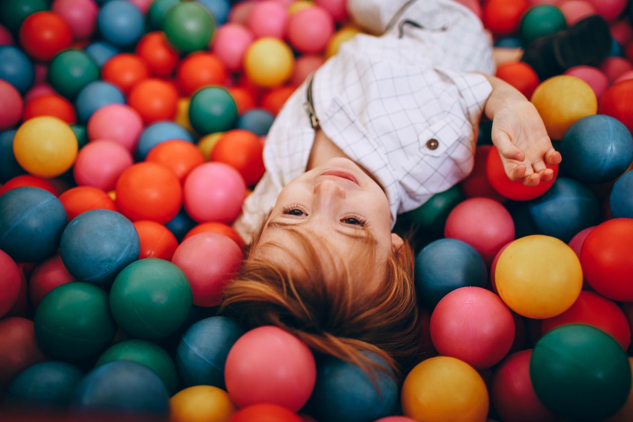 gallery-6 Adorable child enjoying playtime in a vibrant, indoor ball pit.