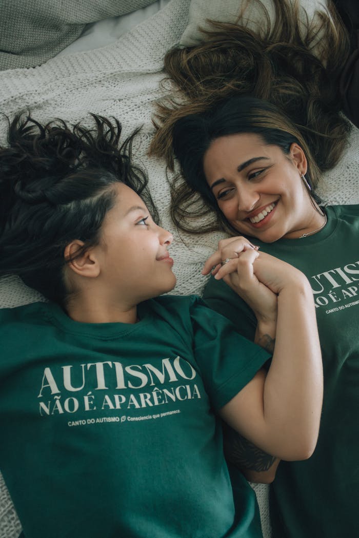 services-03 A mother and child lying on bed, holding hands, promoting autism awareness.