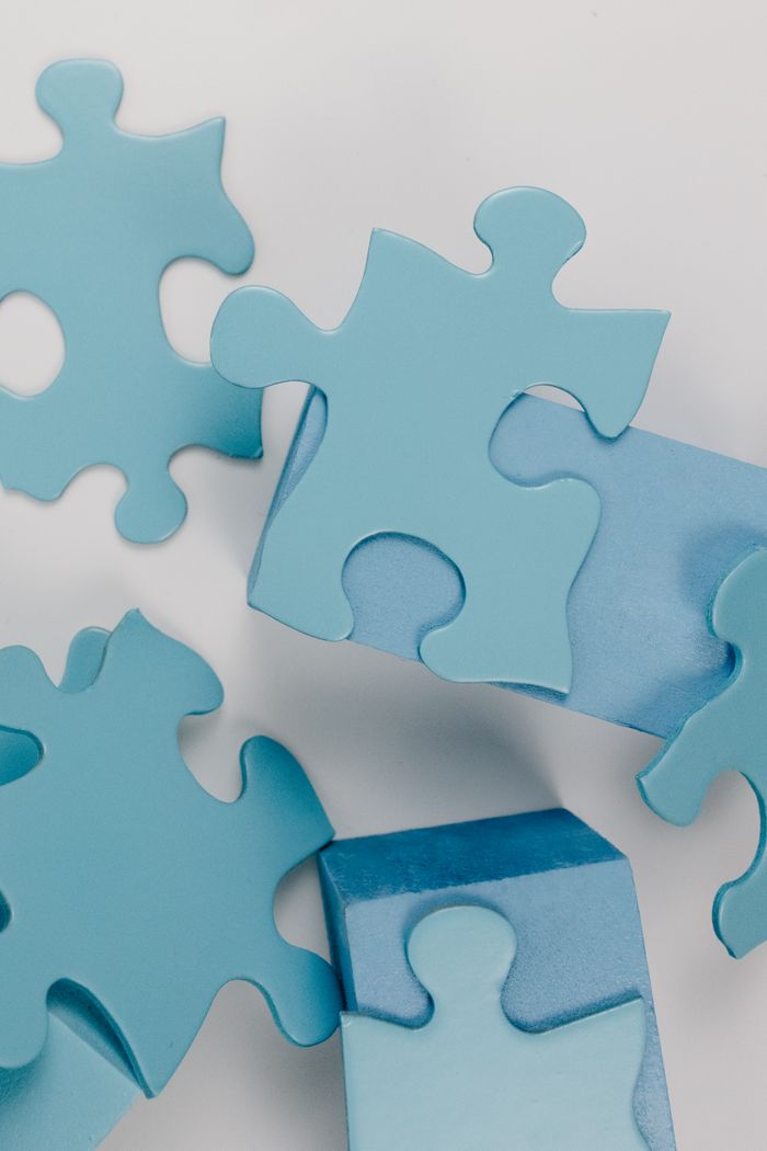 gallery-5 Detailed close-up of blue puzzle pieces randomly arranged on a white background.