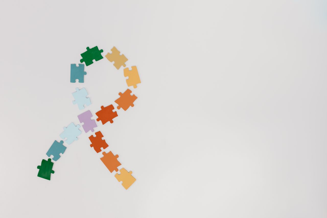 gallery-2 A ribbon shape made from colorful puzzle pieces on a white background symbolizing awareness.