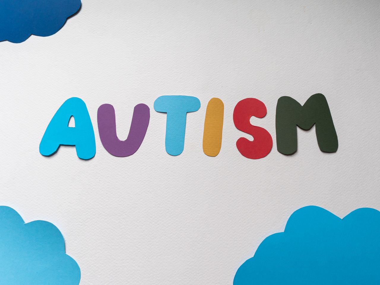 services-04 Colorful cutout letters spell autism on a white background with clouds representing awareness.